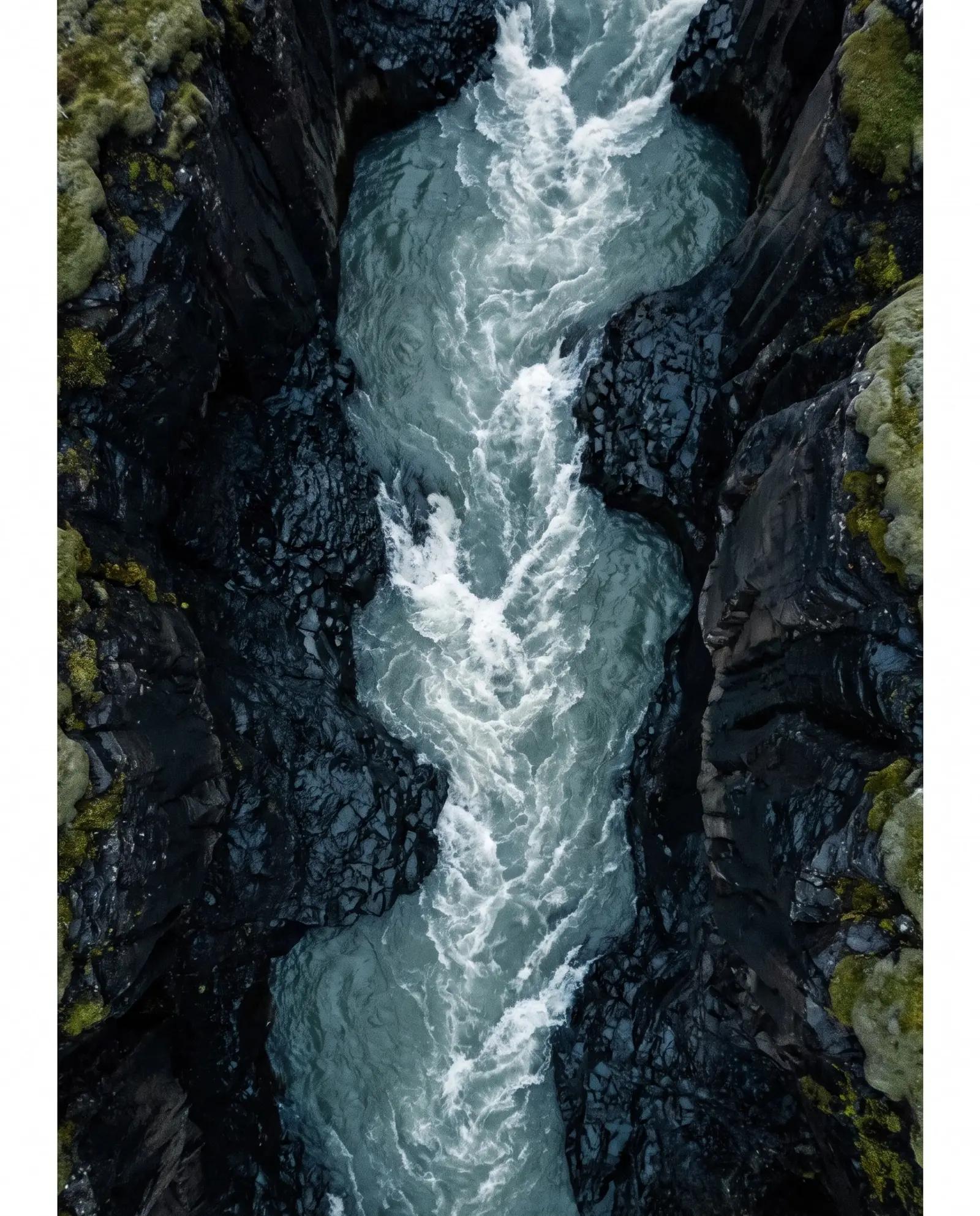 Glacial river roaring between black basalt walls, seen from above