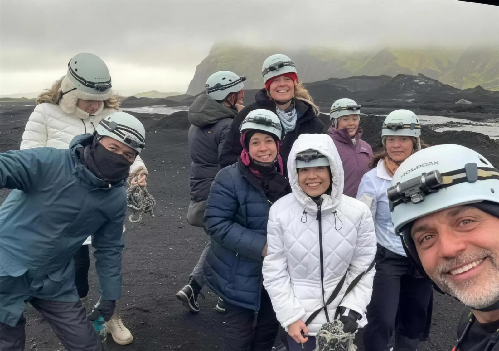 Group of travelers in helmets on a black-sand lava field